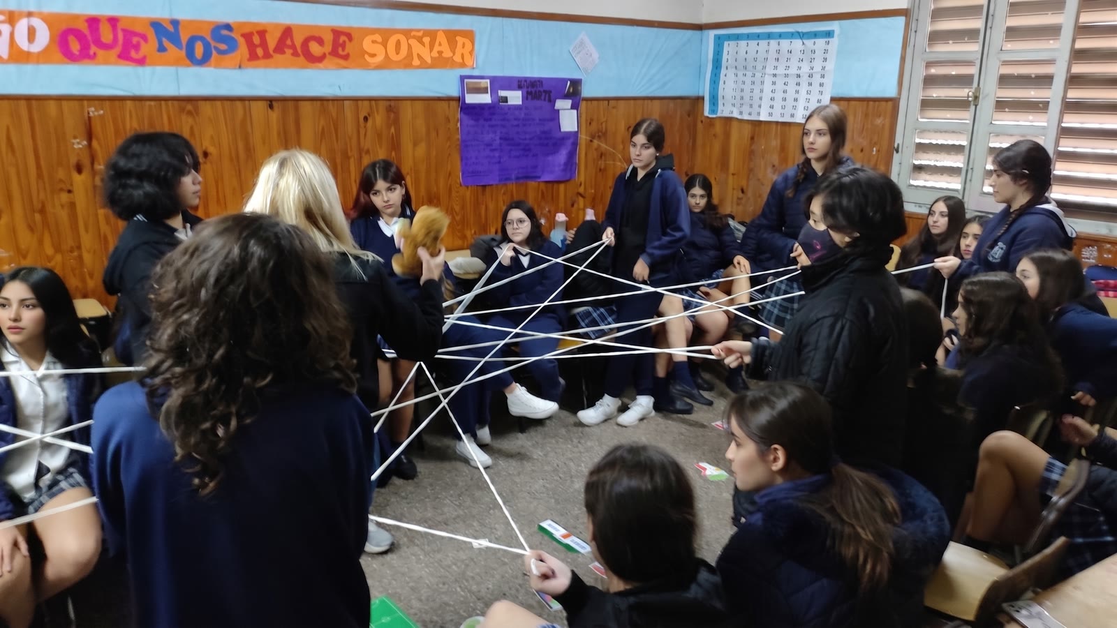 Estudiantes tejiendo una red de hilo en un taller de prevención