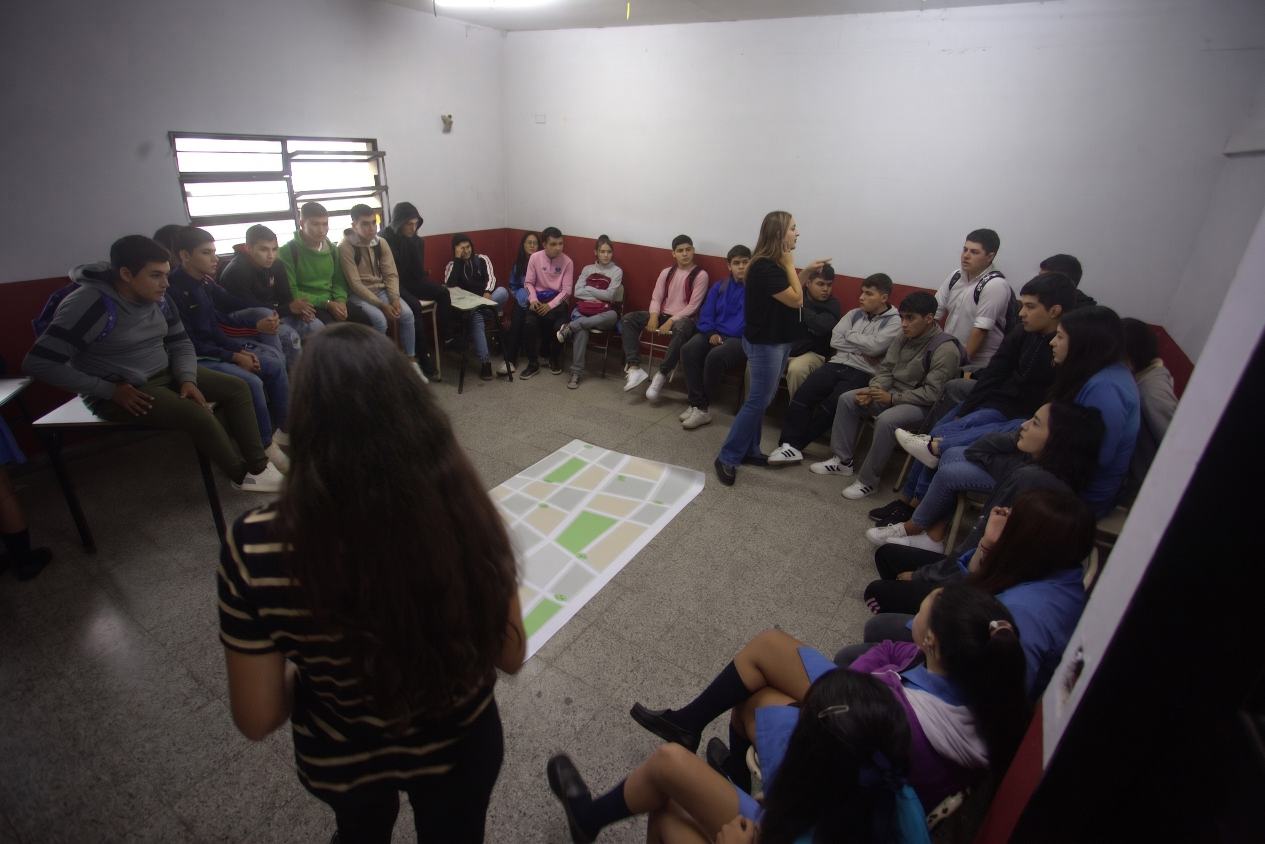 Estudiantes en ronda alrededor de un mapa durante una dinámica de taller