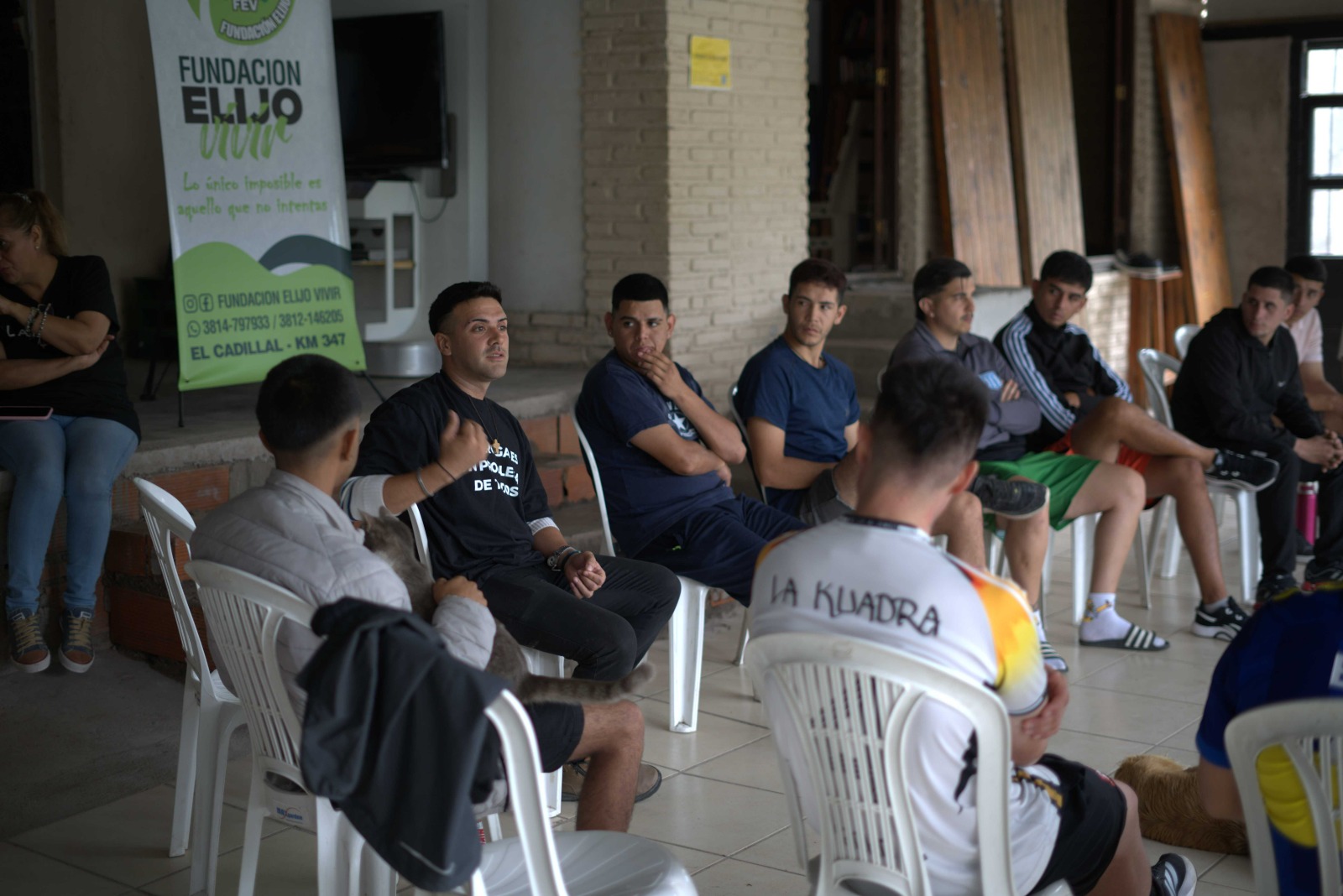 Coordinador hablando con un grupo de jóvenes junto al banner de la Fundación Elijo Vivir
